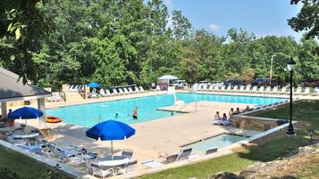 A pool area with lounge chairs and umbrellas, surrounded by trees.