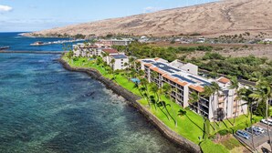 A coastal hotel with multiple buildings, a marina, and wind turbines in the background. - SUMMER SALE! 2BD OceanFront Getaway w AC Pool - Lauloa 105 (Wailuku)