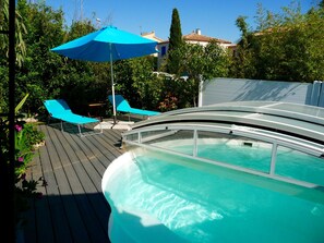 Une piscine avec une terrasse en bois et des chaises longues bleues.