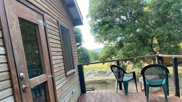 A wooden deck with a glass door, two chairs, and a table.