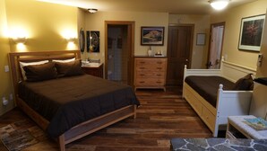 Un dormitorio con una cama de madera, un aparador, una mesita de noche y una pequeña mesa.