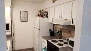A compact kitchen with white cabinets, a refrigerator, a stove, and a microwave. - Old Town Scottsdale Getaway - Spectacular Pool View (Scottsdale)