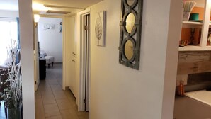 A hallway with a white door, a decorative mirror, and a kitchen area with a stove and cabinets. - Old Town Scottsdale Getaway - Spectacular Pool View (Scottsdale)