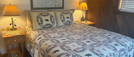 Quarto com uma cama, duas mesas de cabeceira, um mapa na parede e uma janela com persianas.
