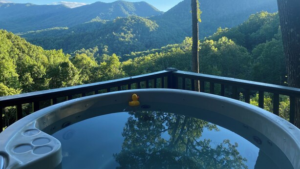 A hot tub with a view of a forested mountain range.