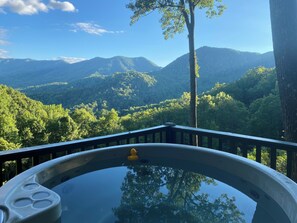 Un bain à remous avec vue sur une chaîne de montagnes boisées.