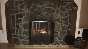 A stone fireplace with a glass door, a woven basket, and a welcome sign.