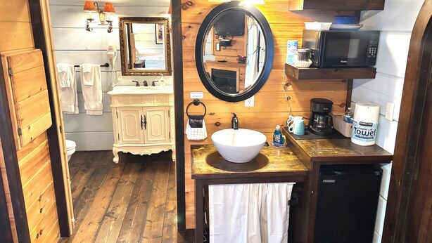 A wooden interior with a white sink, vanity, and a microwave. - #7 Tilly - Tiny Home Cottage (Sevierville)