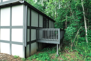 A building with a balcony, surrounded by dense forest.
