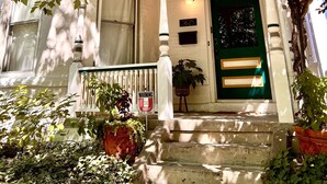 A two-story building with a green door, white columns, and a balcony.