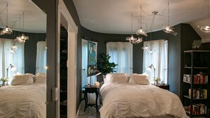A bedroom with two beds, a large mirror, a desk, and a bookshelf.