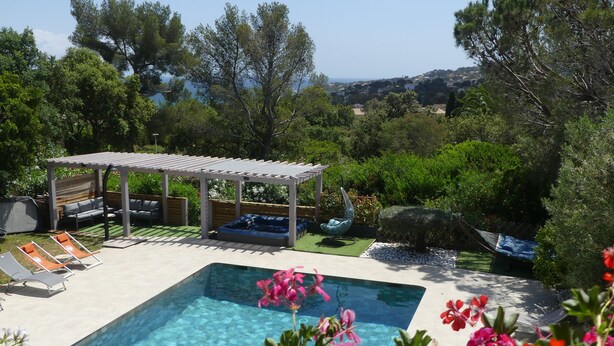 Una piscina con lettini e una vasca idromassaggio, immersa nel verde con vista sulle colline.