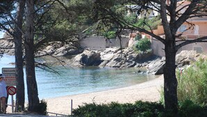 Una strada costiera con spiaggia e affioramenti rocciosi.