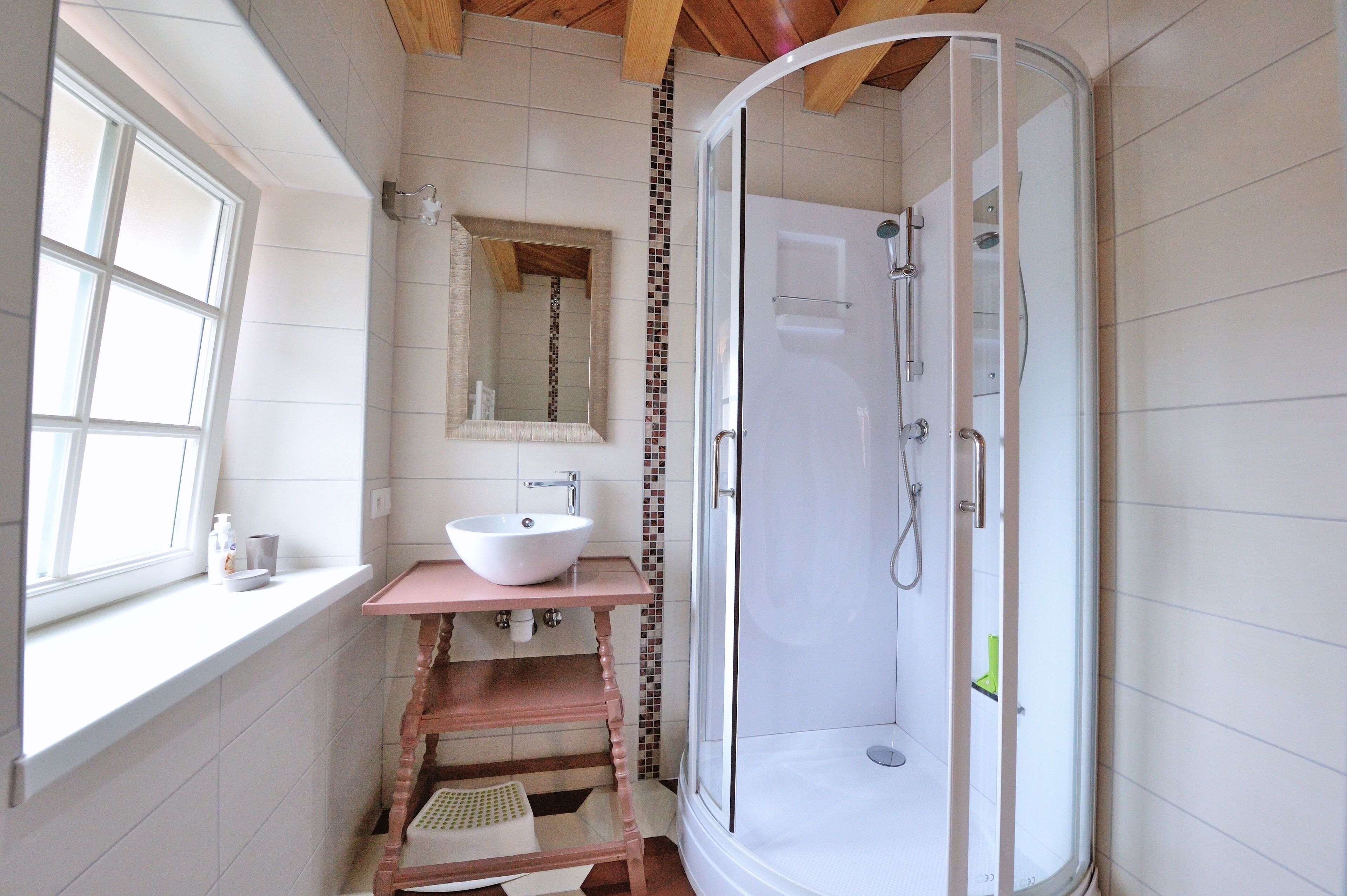 A bathroom with a glass-enclosed shower, a white sink, and a window.