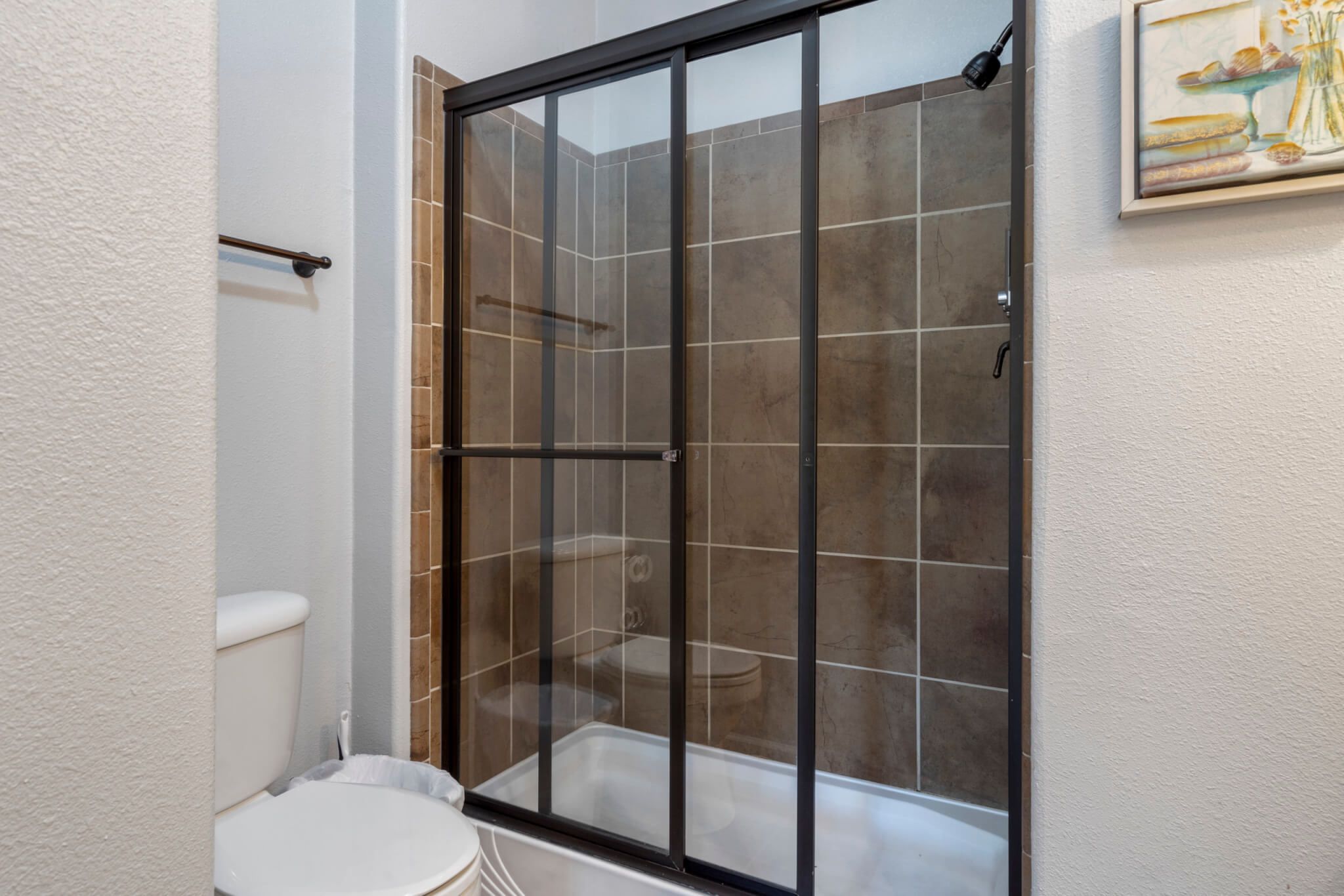 Un baño con ducha de vidrio, inodoro y perchero para toallas.