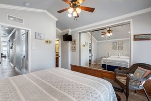 Une chambre à coucher avec un grand lit, un ventilateur de plafond, une armoire et un miroir.