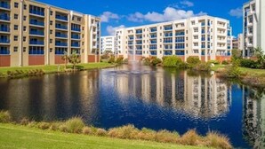A multi-story hotel with a central courtyard featuring a reflective water body and a fountain. - Ocean Oasis (Volusia County)