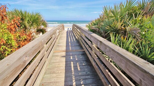 A wooden boardwalk leading to a beach with ocean views. - Ocean Oasis (Volusia County)