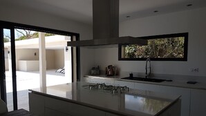 Uma cozinha moderna com ilha central, forno embutido e janela com vista para o verde.