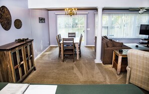 Ein Wohnzimmer mit Essbereich, einer Couch, einem Fernseher und einer Deckenleuchte.