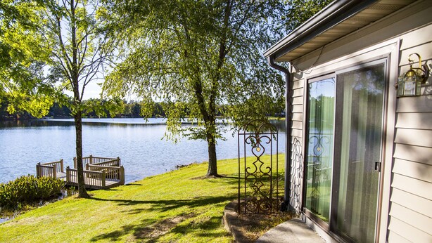 A lakeside property with a deck, a screened porch, and a view of the water.