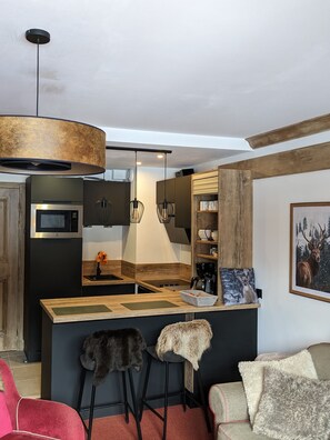 Une cuisine moderne dotée d’un îlot central, d’un luminaire suspendu et d’un four à micro-ondes.