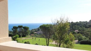 Ein Balkon mit Blick auf einen Golfplatz, Bäume und eine entfernte Küstenlinie.