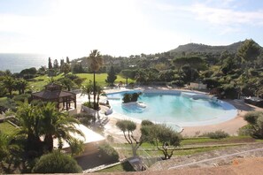 A pool area with a gazebo, surrounded by greenery and hills in the background.