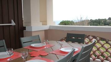An outdoor dining area with a table set for four, chairs, and a view of the landscape.