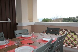 An outdoor dining area with a table set for four, chairs, and a view of the landscape.