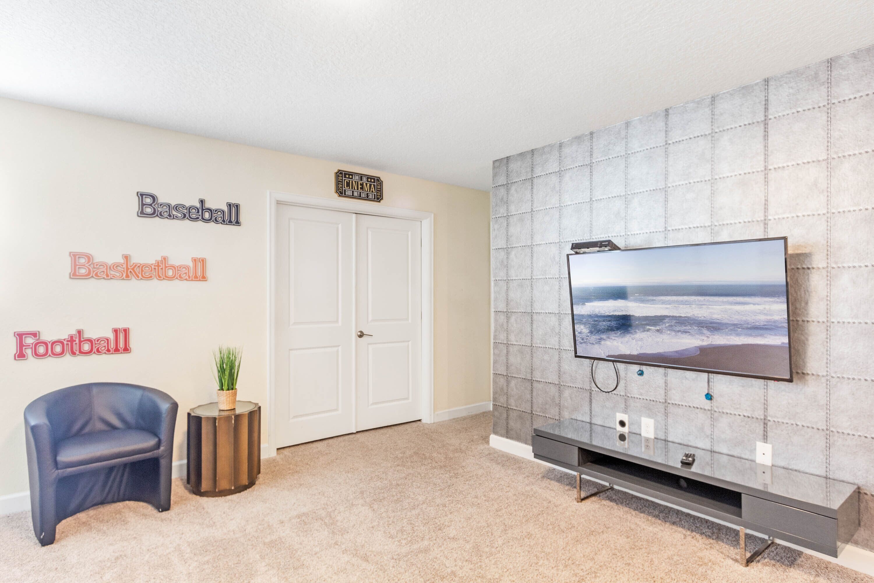 A living room with a TV, a couch, and a wall with sports-themed decorations.