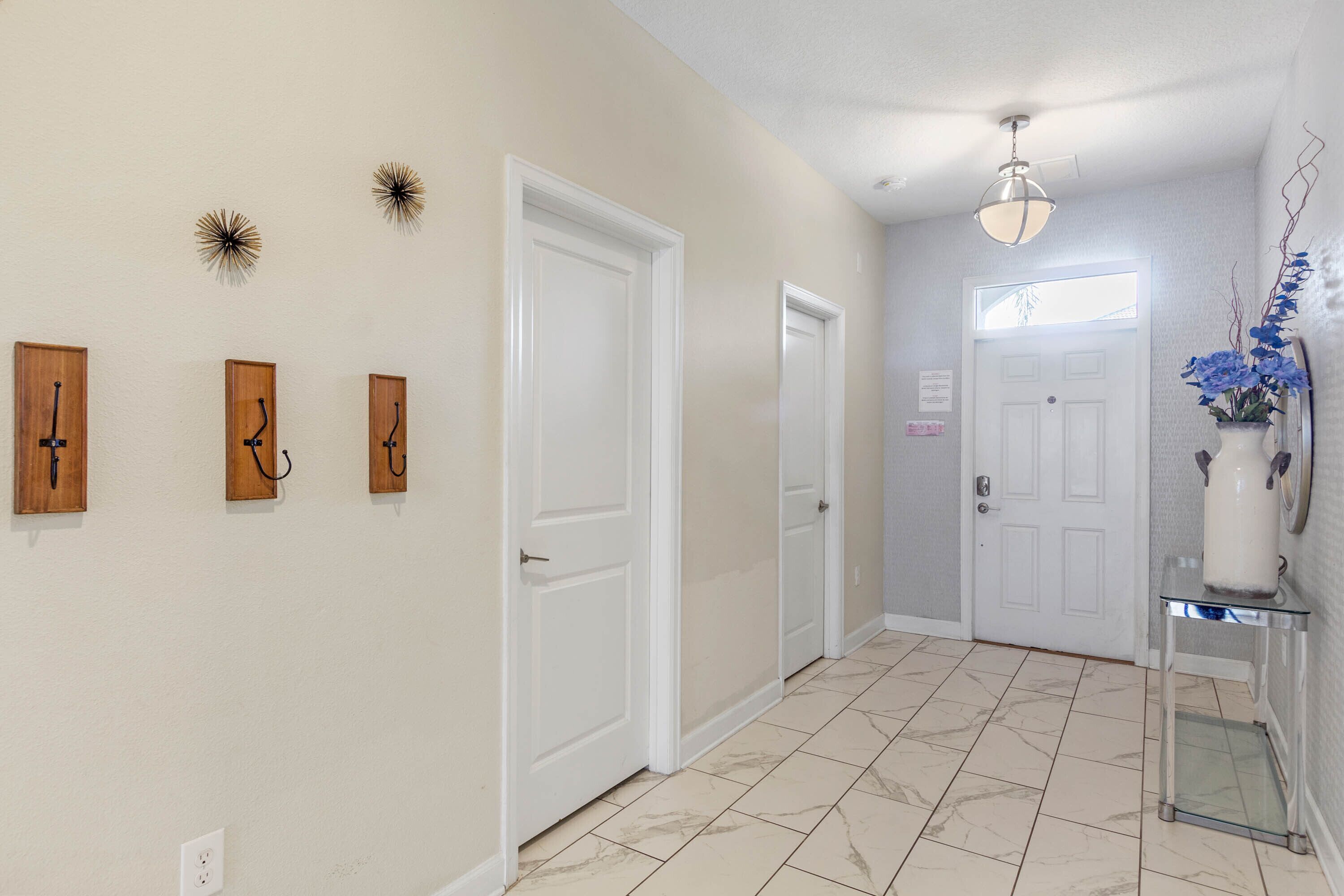 A hallway with white doors, a tiled floor, and wall-mounted decorations.