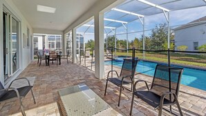 Une terrasse couverte avec une piscine, des sièges d’extérieur et une vue sur le jardin arrière.