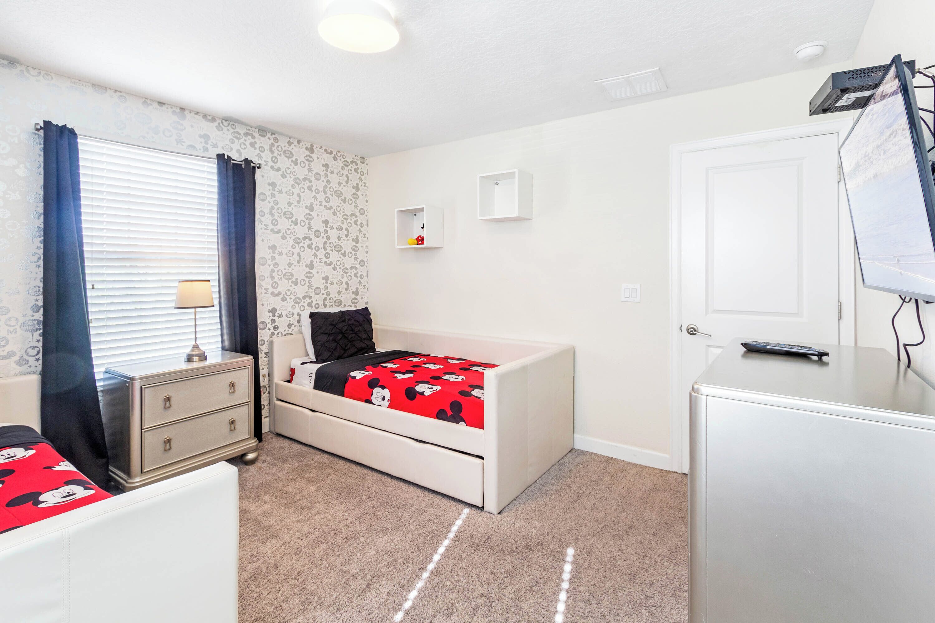 A bedroom with a bed, dresser, and a TV stand.