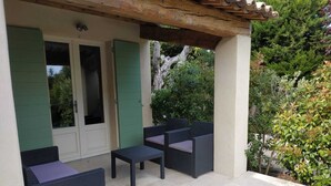 An outdoor patio area with a pergola, two doors, and a seating arrangement.