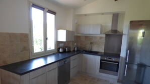 A modern kitchen with a dishwasher, oven, and stainless steel refrigerator.
