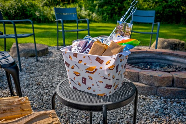 A basket filled with snacks and drinks on a metal table outdoors.