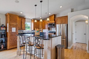A modern kitchen with wooden cabinets, stainless steel appliances, and a central island with bar stools.