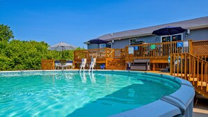 Une piscine avec une terrasse en bois et des chaises longues.