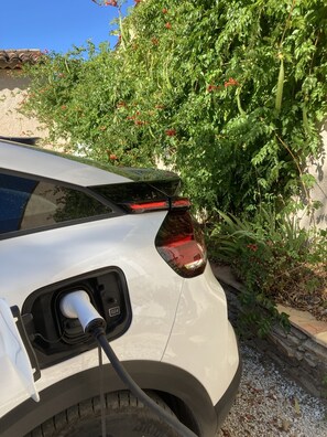 A car parked with a charging cable connected to the rear charging port.