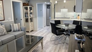 A modern kitchen with white cabinets, a central island, and black chairs around a glass table. - One block to beach and to dining. Best location in Naples !! (Naples)