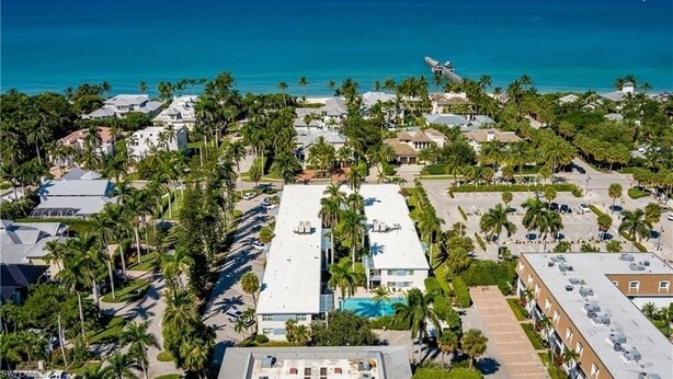An aerial view of a coastal residential area with houses, palm trees, and a clear view of the ocean. - One block to beach and to dining. Best location in Naples !! (Naples)
