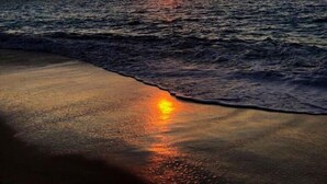 Ein Sonnenuntergang über dem Meer mit an die Küste rollenden Wellen.