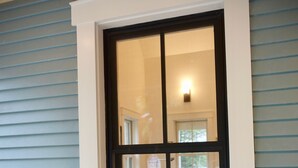 A window with a white frame and black trim, reflecting a room with a lamp and a chair. - New! Vermont modern farmhouse in Stowe Village (Stowe)