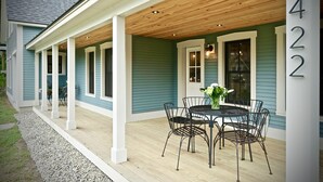 A covered porch with a wooden ceiling, a dining table with chairs, and a number '422' on the wall. - New! Vermont modern farmhouse in Stowe Village (Stowe)