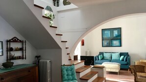 Een woonkamer met een trap, een bank, een stoel en een radiator.