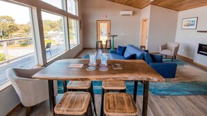 Ein modernes Interieur mit einem Holztisch, Hockern, einem blauen Sofa und einem Kamin.