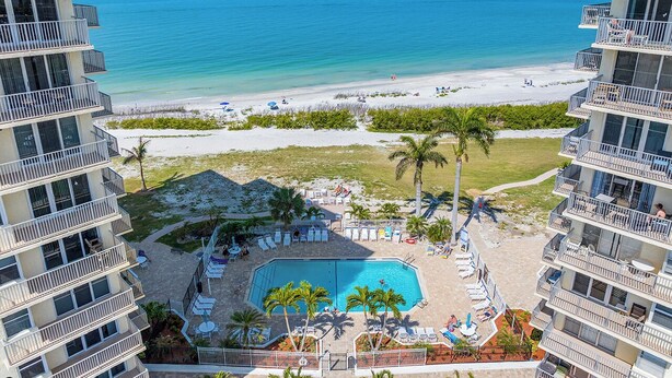 A hotel with a pool, beach view, and multiple balconies.