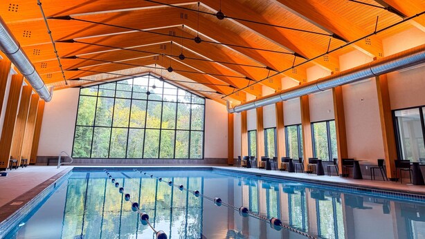 A swimming pool with clear water, surrounded by wooden beams and large windows. - Spacious Lakefront Villa I 4 BD 3 Bath I Sleeps 11 I Ski I Golf I Bike (Biwabik)