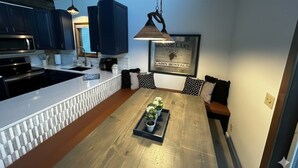 A modern kitchen with dark blue cabinets, a white countertop, and a hanging pendant light. A framed picture of Moose Lake and Cabin Rentals is on the wall. - Spacious Lakefront Villa I 4 BD 3 Bath I Sleeps 11 I Ski I Golf I Bike (Biwabik)
